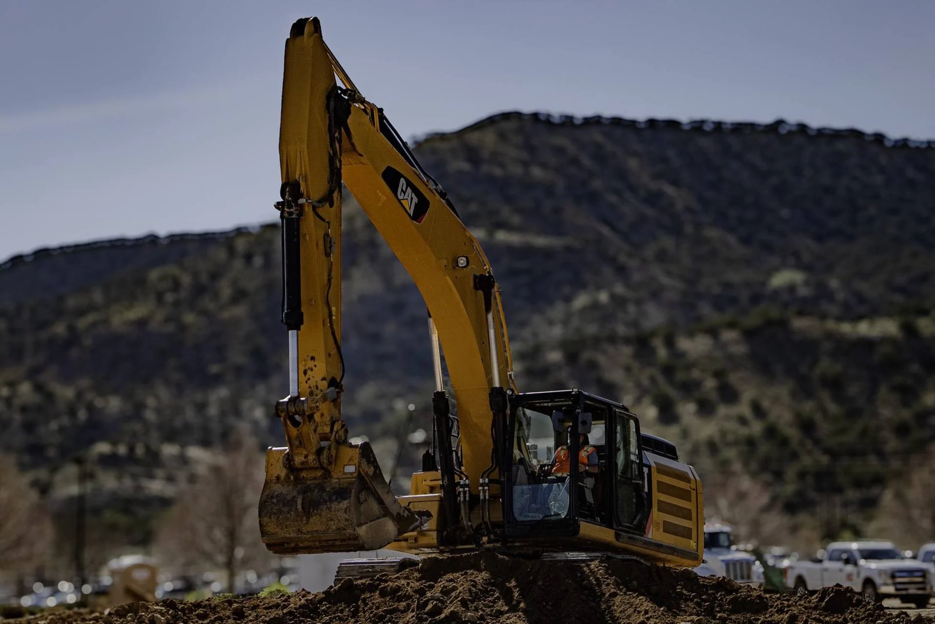 A Cat excavator working under a highway bridge