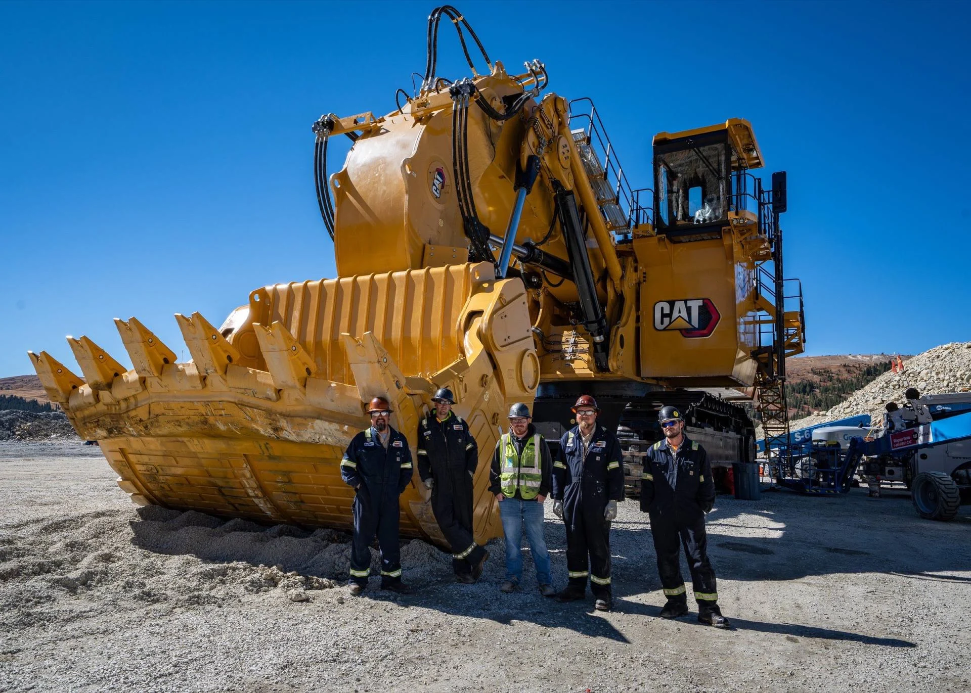 A Cat mining shovel with the crew standing alongside